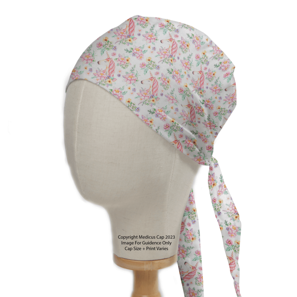 Unicorns Flower Power Scrub Cap by Medicus Scrub Caps: A floral-patterned fabric cap on a mannequin, featuring pink and green flowers with ribbon-like designs on white. The elegant ties hang down the side, blending style and whimsy in sustainable healthcare fashion.