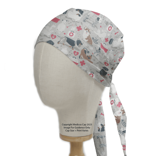 A mannequin displays the Vet Clinic Surgery Scrub Cap by Medicus Scrub Caps, featuring cats, dogs, medical symbols, and pink hearts on a white background. Ideal for veterinary professionals, its noted as a copyrighted sample from Medicus Cap 2023.