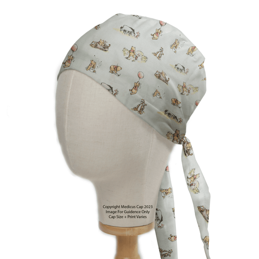 Side view of the sustainable Winnie The Pooh #2 Green Scrub Cap by Medicus Scrub Caps on a mannequin head, showcasing light fabric with vibrant animal and balloon patterns. Perfect for healthcare professionals, it includes printed text at the bottom for an added touch.