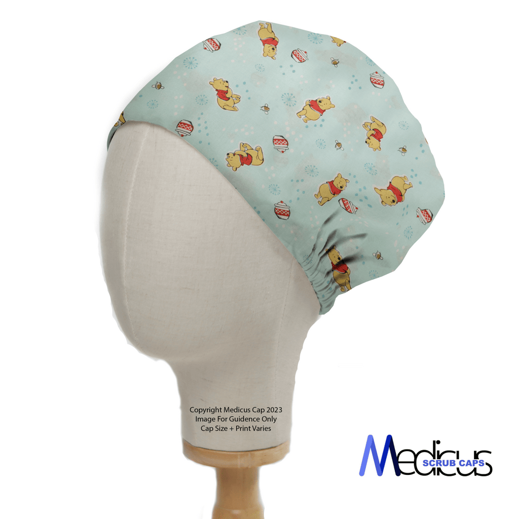 The Winnie The Pooh #5 - Honey Pot Scrub Cap by Medicus Scrub Caps is shown on a mannequin head, highlighting a light blue background with cartoon bears, snowflakes, and striped ornaments. Its designed for healthcare professionals and features the logo in the bottom right corner.