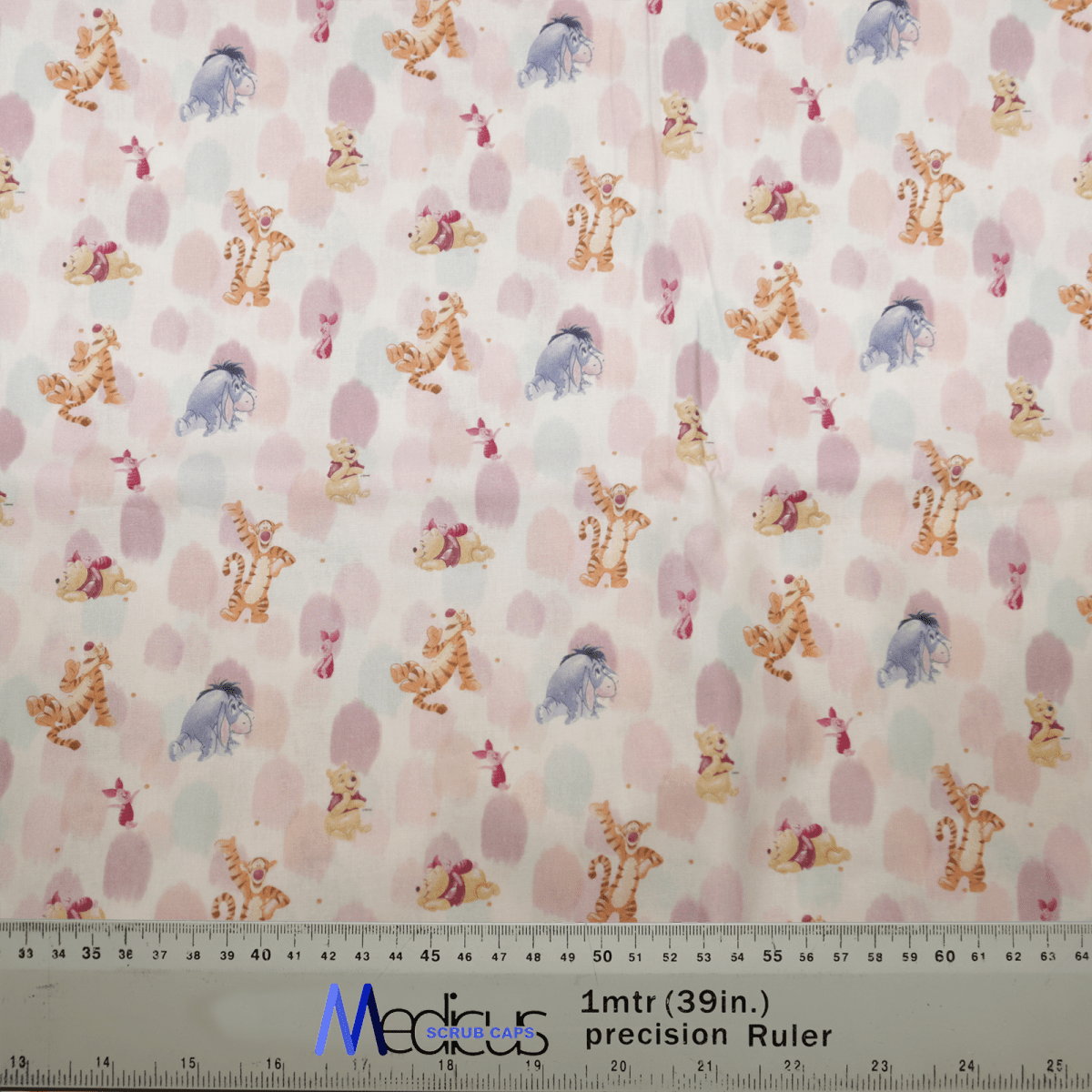 The Medicus Scrub Caps Winnie The Pooh + Friends Finger Paint features a playful pattern with cartoon tigers, elephants, and bears on white, adorned with pink polka dots. A ruler is at the bottom edge for scale.