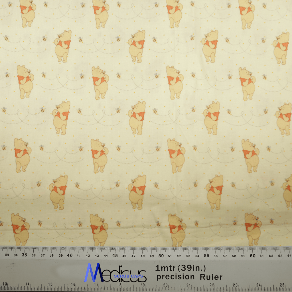 The Winnie The Pooh Honey + Bees Scrub Cap by Medicus Scrub Caps showcases a playful pattern of Winnie The Pooh and bees. It features a ruler with measurements in centimeters and inches, perfect for creating whimsical scrub cap designs.
