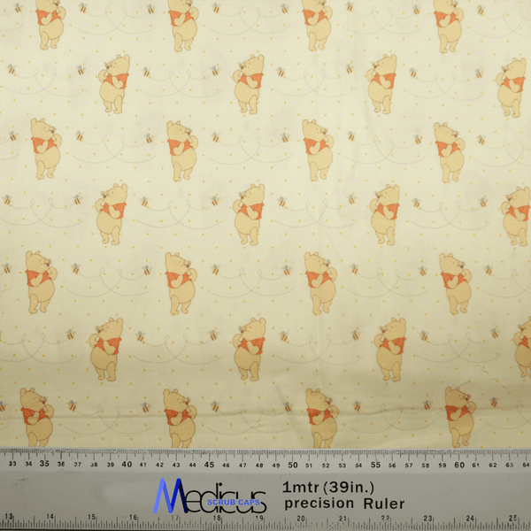 The Winnie The Pooh Honey + Bees Scrub Cap by Medicus Scrub Caps showcases a playful pattern of Winnie The Pooh and bees. It features a ruler with measurements in centimeters and inches, perfect for creating whimsical scrub cap designs.
