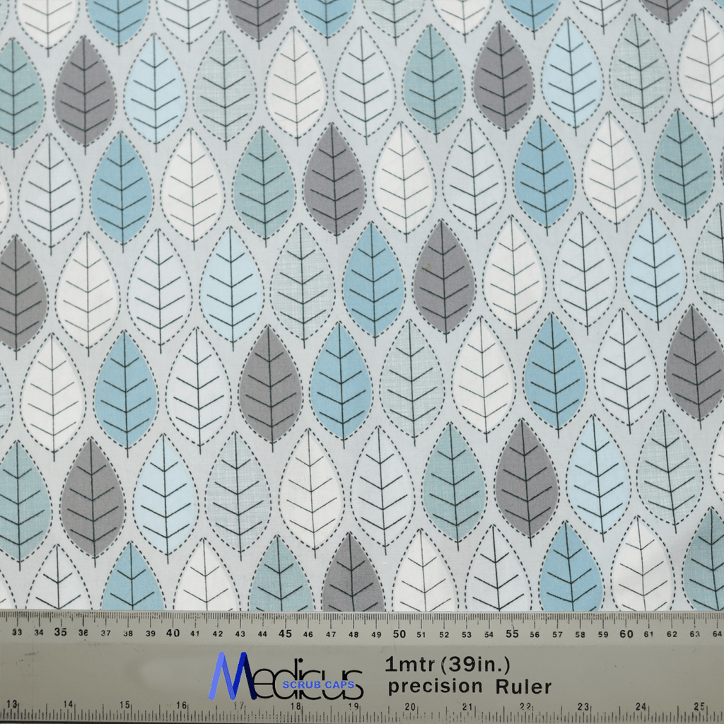 Medicus Scrub Caps Winter Leaves Scrub Cap features a calming leaf pattern in blue, gray, and white. The leaves are arranged in alternating rows, and a metal ruler at the bottom provides measurements in both meters and inches.