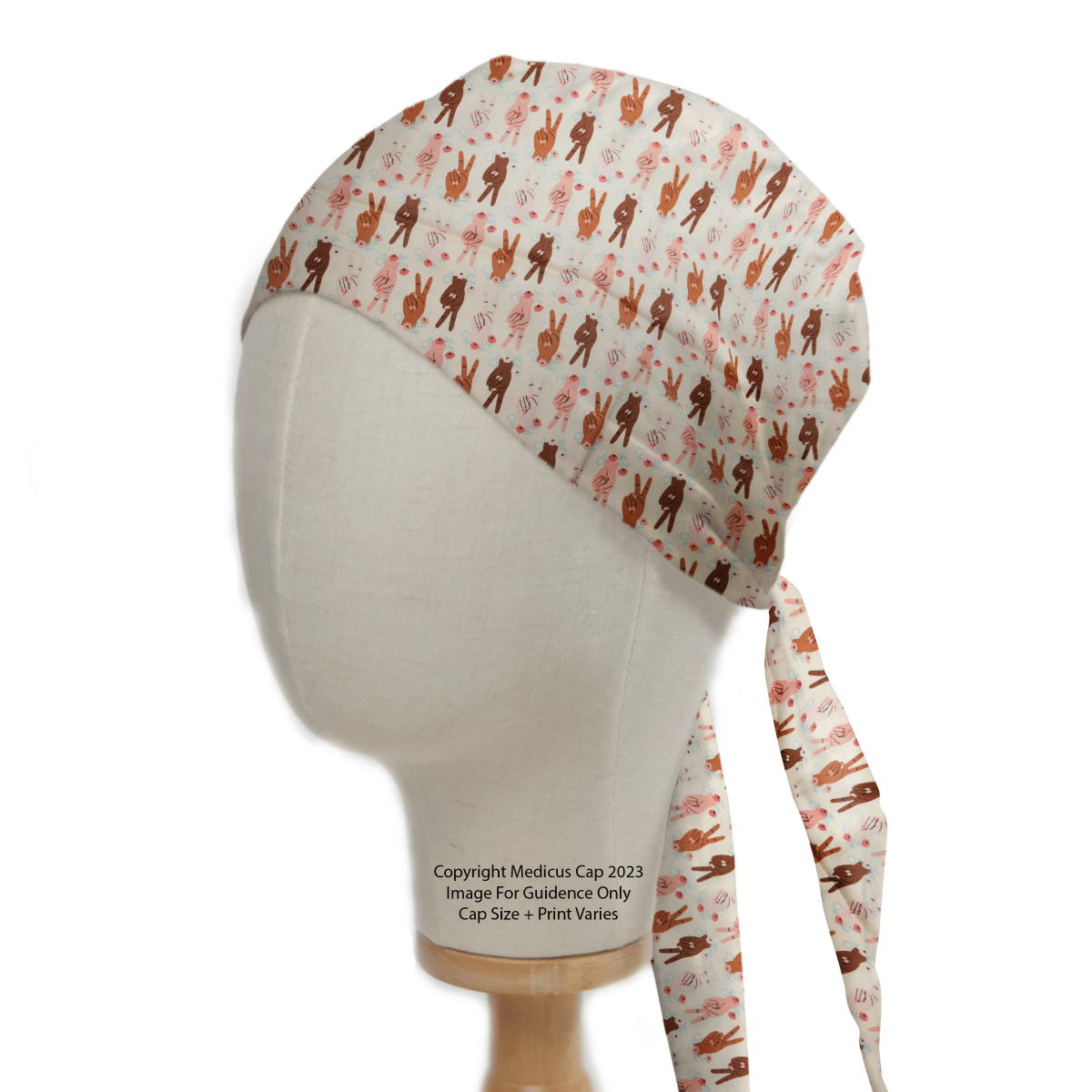 A mannequin head showcases the Women Peace Sign Empowerment Scrub Cap by Medicus Scrub Caps, featuring a playful brown and pink bunny pattern on a white background, with ties at the back, ideal for healthcare professionals.